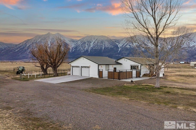 view of front of house with concrete driveway, a garage, fence, and a mountain view