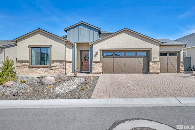 view of front of home with board and batten siding, stucco siding, decorative driveway, stone siding, and an attached garage