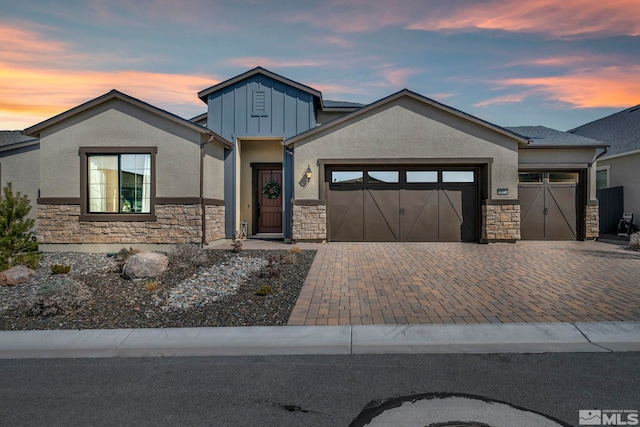 view of front of house with a garage, stone siding, board and batten siding, and decorative driveway