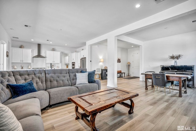 living room with recessed lighting, visible vents, and light wood finished floors