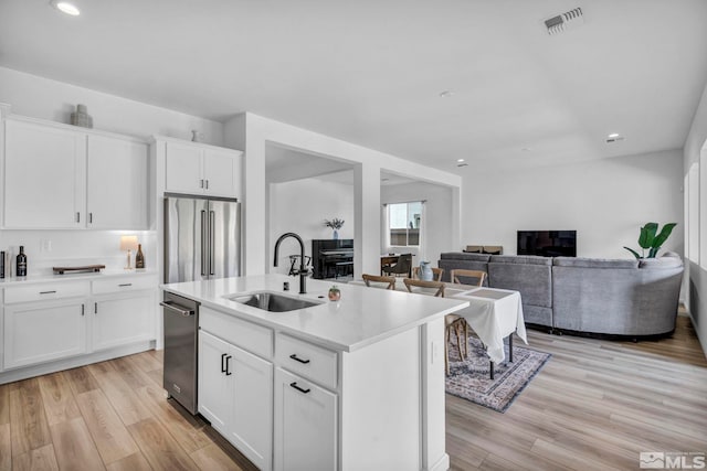 kitchen featuring visible vents, light wood finished floors, a sink, high quality fridge, and light countertops