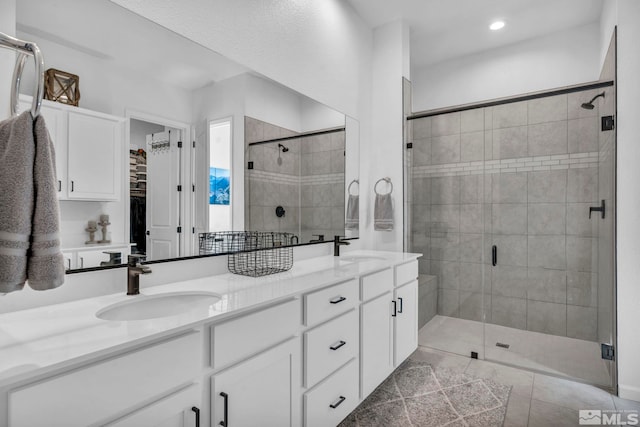 bathroom featuring double vanity, a stall shower, tile patterned floors, and a sink