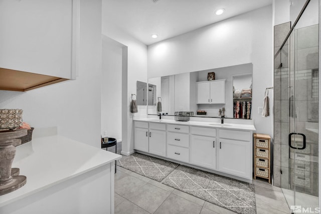 full bathroom with tile patterned flooring, double vanity, a stall shower, and a sink