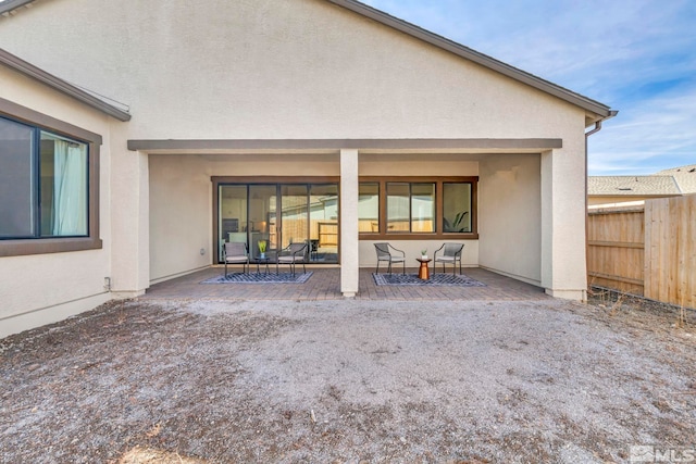 rear view of property featuring stucco siding, a patio, and fence