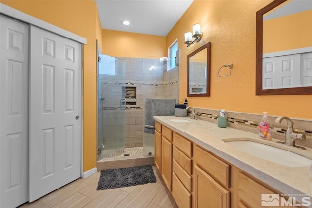 full bathroom with double vanity, a shower stall, tasteful backsplash, and a sink