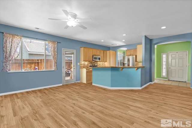 kitchen with tasteful backsplash, visible vents, light brown cabinets, light wood-style flooring, and stainless steel refrigerator with ice dispenser