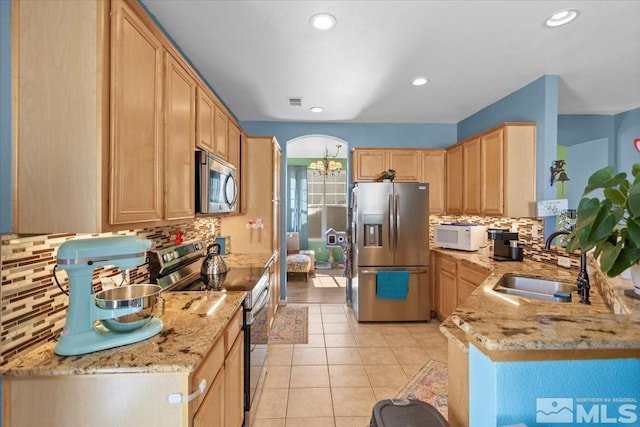 kitchen featuring a sink, light stone counters, appliances with stainless steel finishes, and light tile patterned flooring