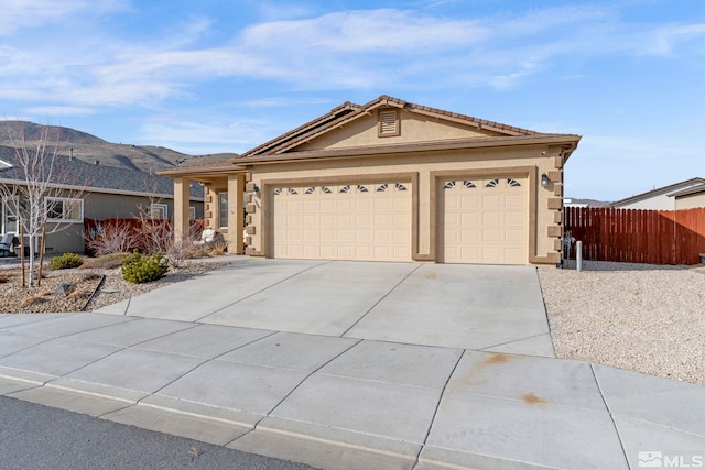 ranch-style house with fence, an attached garage, stucco siding, concrete driveway, and a mountain view