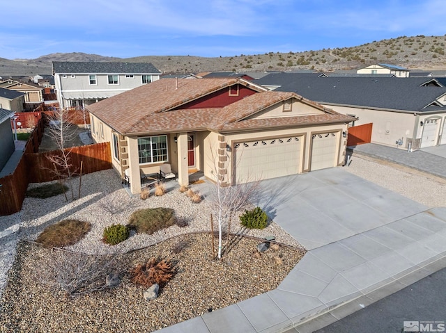 view of front of property with fence, roof with shingles, stucco siding, concrete driveway, and a garage