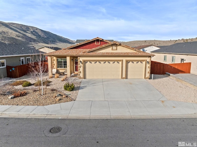 ranch-style home featuring stucco siding, driveway, fence, a mountain view, and an attached garage