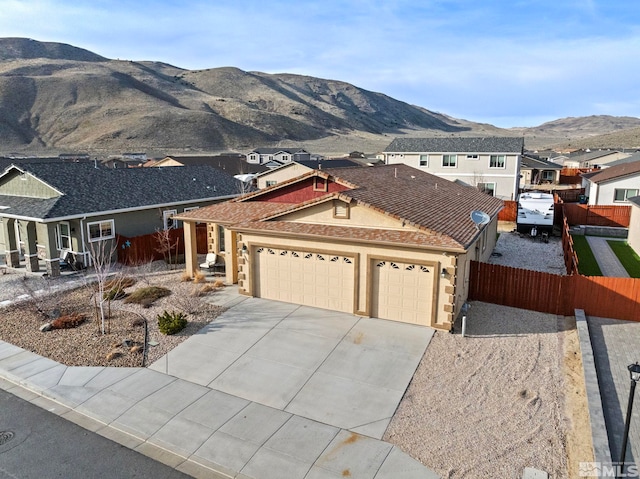 view of front of house featuring an attached garage, fence, concrete driveway, stucco siding, and a mountain view