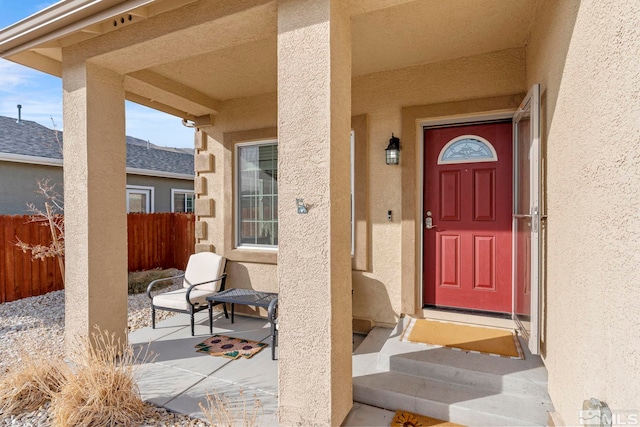 doorway to property with stucco siding and fence