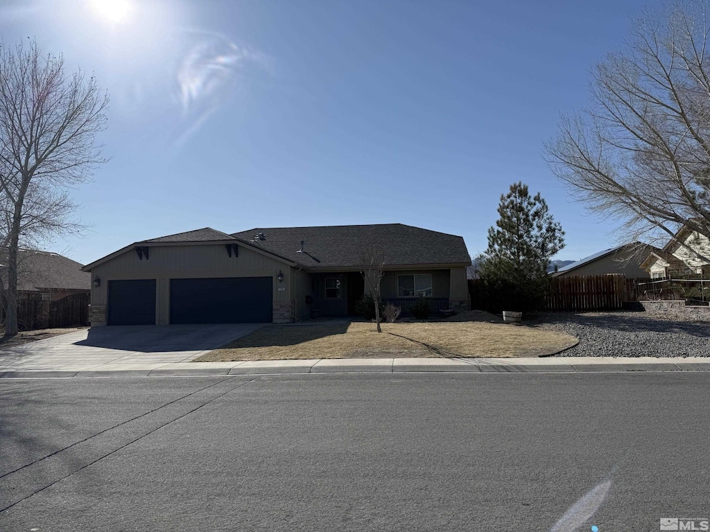 view of front of property with stone siding, fence, a garage, and driveway