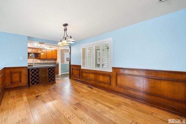 dining area featuring visible vents, wainscoting, and light wood finished floors