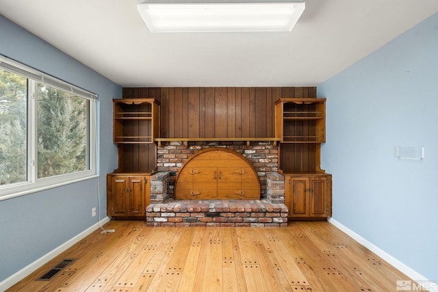 unfurnished living room featuring visible vents, plenty of natural light, baseboards, and hardwood / wood-style flooring