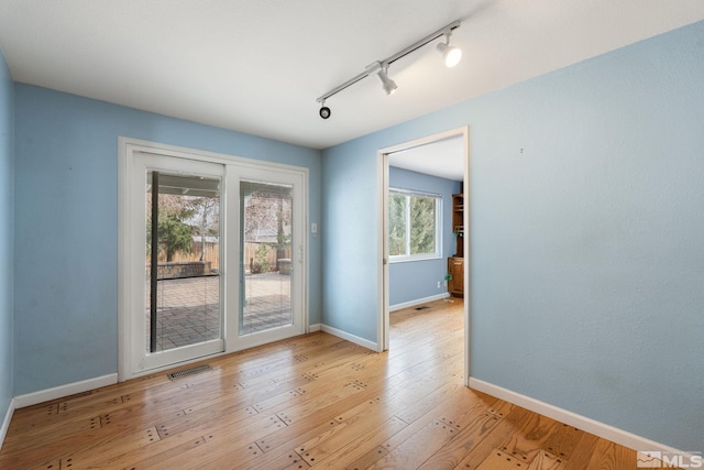 empty room with visible vents, light wood-type flooring, and baseboards