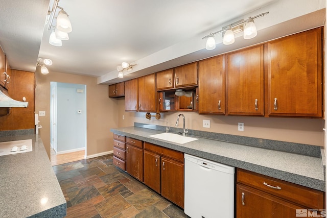 kitchen featuring brown cabinets, a sink, stone finish flooring, white dishwasher, and baseboards