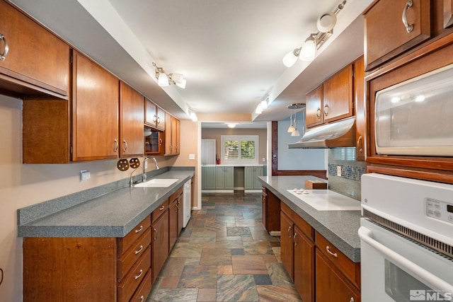 kitchen with white appliances, stone finish flooring, brown cabinets, and a sink