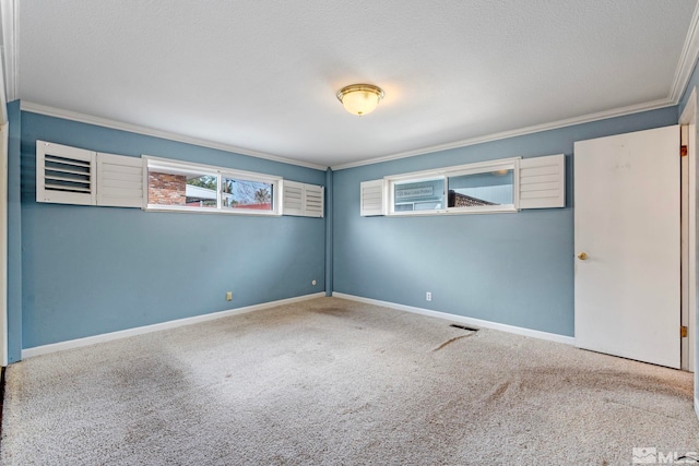 unfurnished room with visible vents, baseboards, ornamental molding, carpet floors, and a textured ceiling