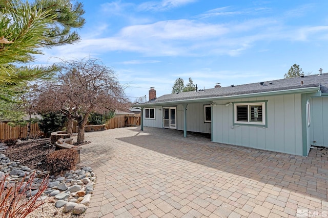 rear view of property with a fenced backyard, a chimney, and a patio area