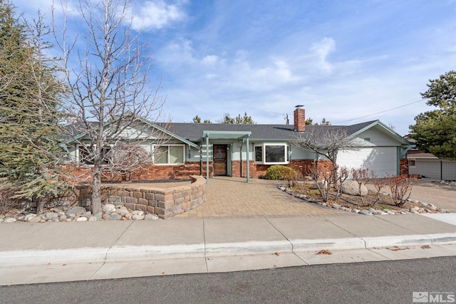 ranch-style home featuring a garage, driveway, brick siding, and a chimney