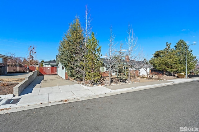 obstructed view of property featuring concrete driveway, central AC unit, and fence