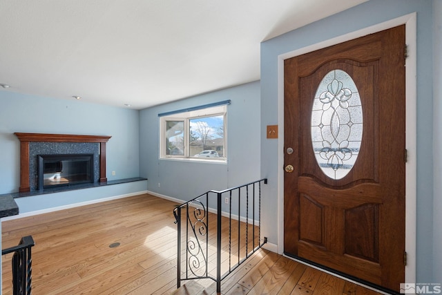 entryway featuring a glass covered fireplace, hardwood / wood-style flooring, and baseboards