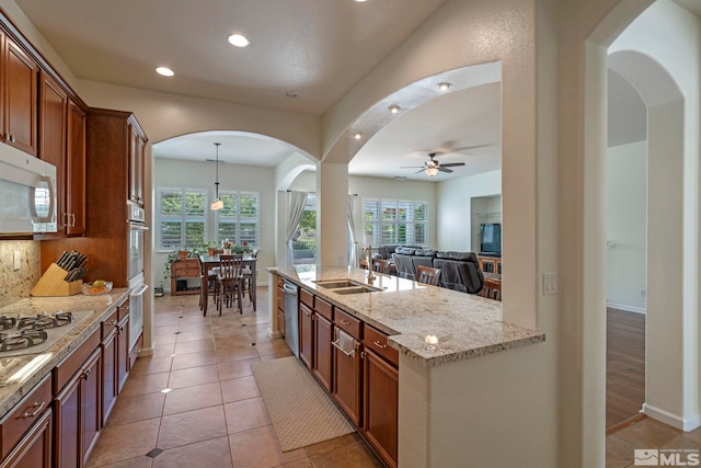 kitchen with light stone counters, appliances with stainless steel finishes, a wealth of natural light, and a sink