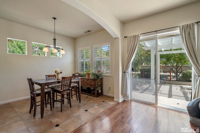 dining space featuring visible vents, light wood-style flooring, arched walkways, baseboards, and a chandelier