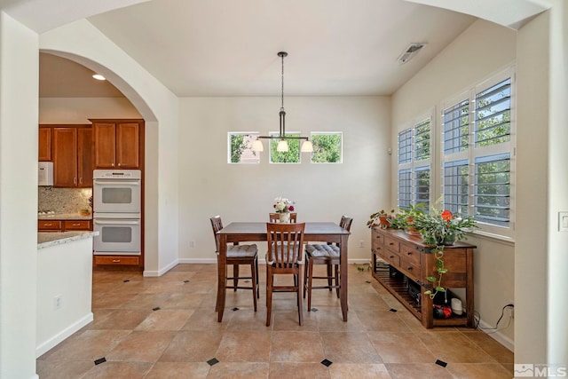 dining room featuring an inviting chandelier, arched walkways, visible vents, and baseboards