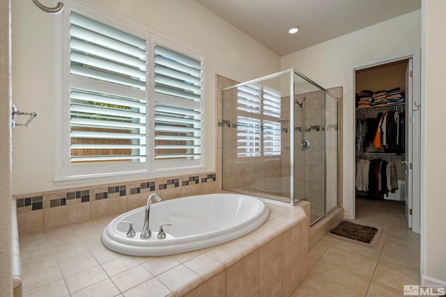 full bath featuring tile patterned floors, a walk in closet, a garden tub, and a stall shower