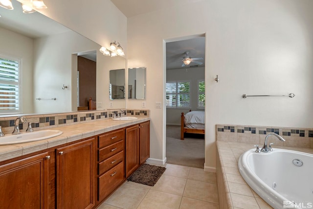 ensuite bathroom with tile patterned flooring, a tub with jets, double vanity, and a sink