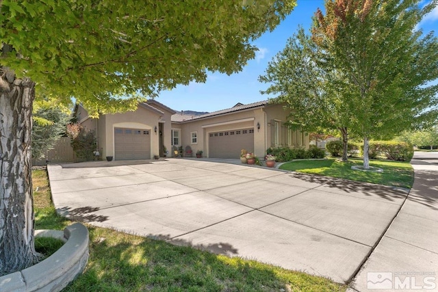 view of front of home featuring a tiled roof, an attached garage, driveway, and stucco siding