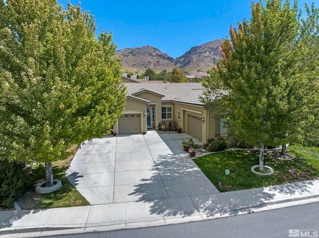 view of front of house with an attached garage, stucco siding, concrete driveway, a tiled roof, and a mountain view