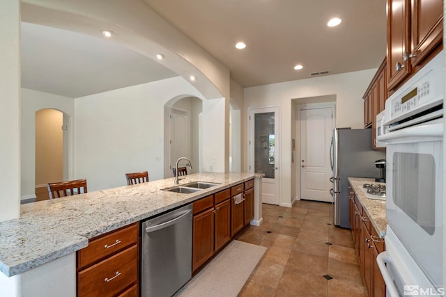 kitchen with brown cabinetry, visible vents, recessed lighting, a sink, and stainless steel dishwasher