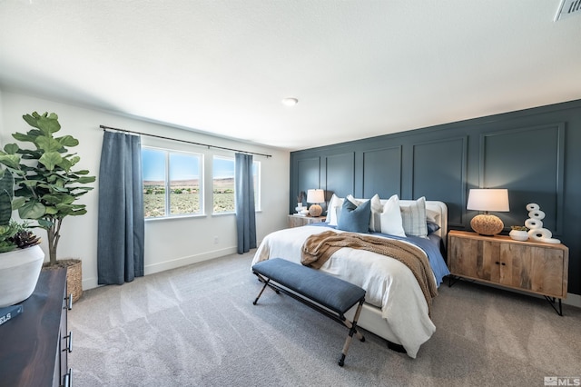 bedroom with light carpet, a decorative wall, baseboards, and visible vents