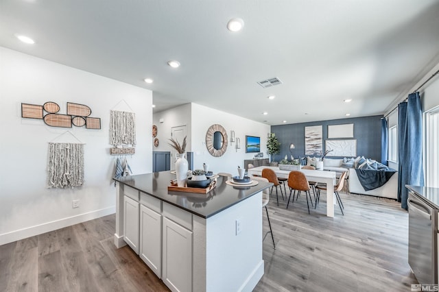 kitchen with visible vents, dark countertops, a center island, and light wood finished floors