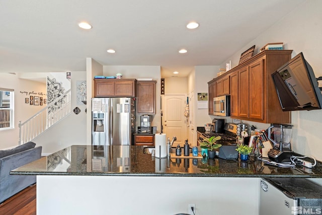 kitchen with dark stone countertops, brown cabinetry, a peninsula, recessed lighting, and appliances with stainless steel finishes