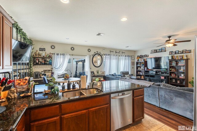 kitchen featuring a ceiling fan, a sink, open floor plan, dark stone counters, and dishwasher