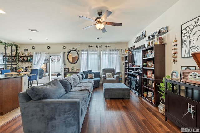 living area featuring dark wood-type flooring, visible vents, and ceiling fan