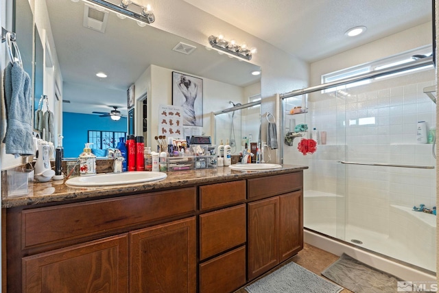 bathroom featuring double vanity, visible vents, a shower stall, and a sink