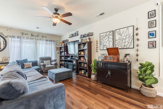 living room with ceiling fan, visible vents, baseboards, and wood finished floors