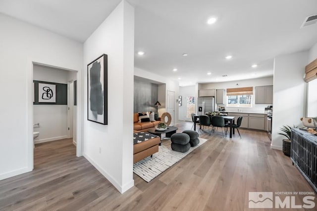 interior space featuring light wood finished floors, visible vents, gray cabinetry, and stainless steel refrigerator with ice dispenser