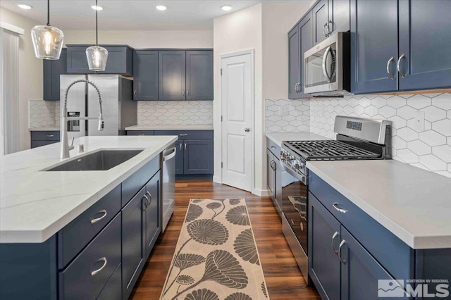 kitchen with dark wood-type flooring, pendant lighting, a sink, stainless steel appliances, and light stone countertops