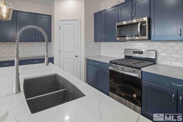 kitchen featuring a sink, decorative backsplash, blue cabinetry, and stainless steel appliances