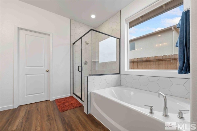 bathroom featuring a garden tub, wood finished floors, a stall shower, and baseboards