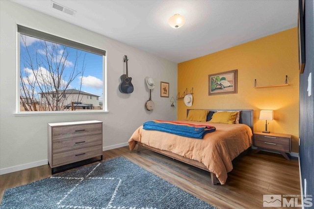 bedroom with visible vents, baseboards, and wood finished floors