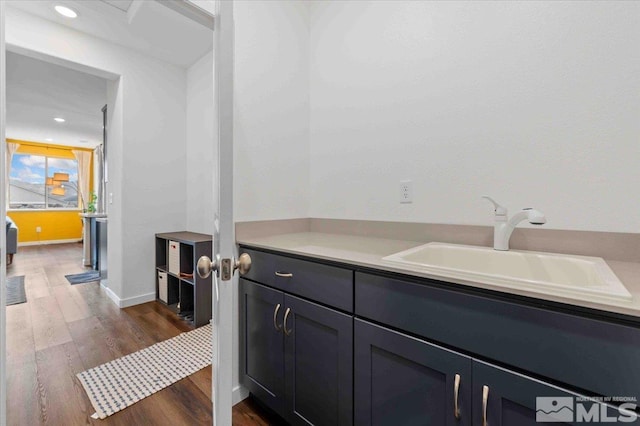 bathroom featuring recessed lighting, wood finished floors, baseboards, and a sink