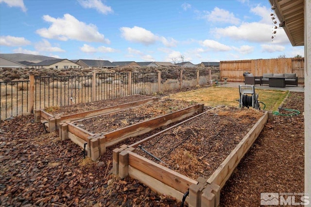 view of yard with a residential view, a vegetable garden, a fenced backyard, and outdoor lounge area