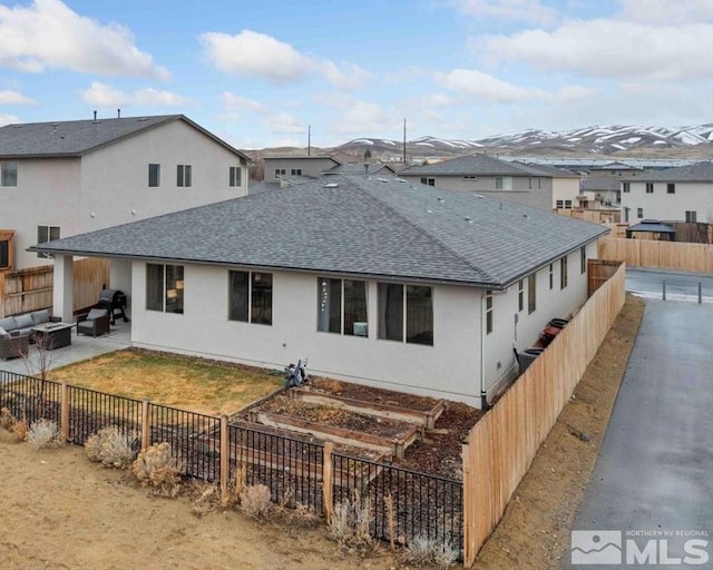 back of house featuring a shingled roof, outdoor lounge area, a fenced backyard, a garden, and a patio area